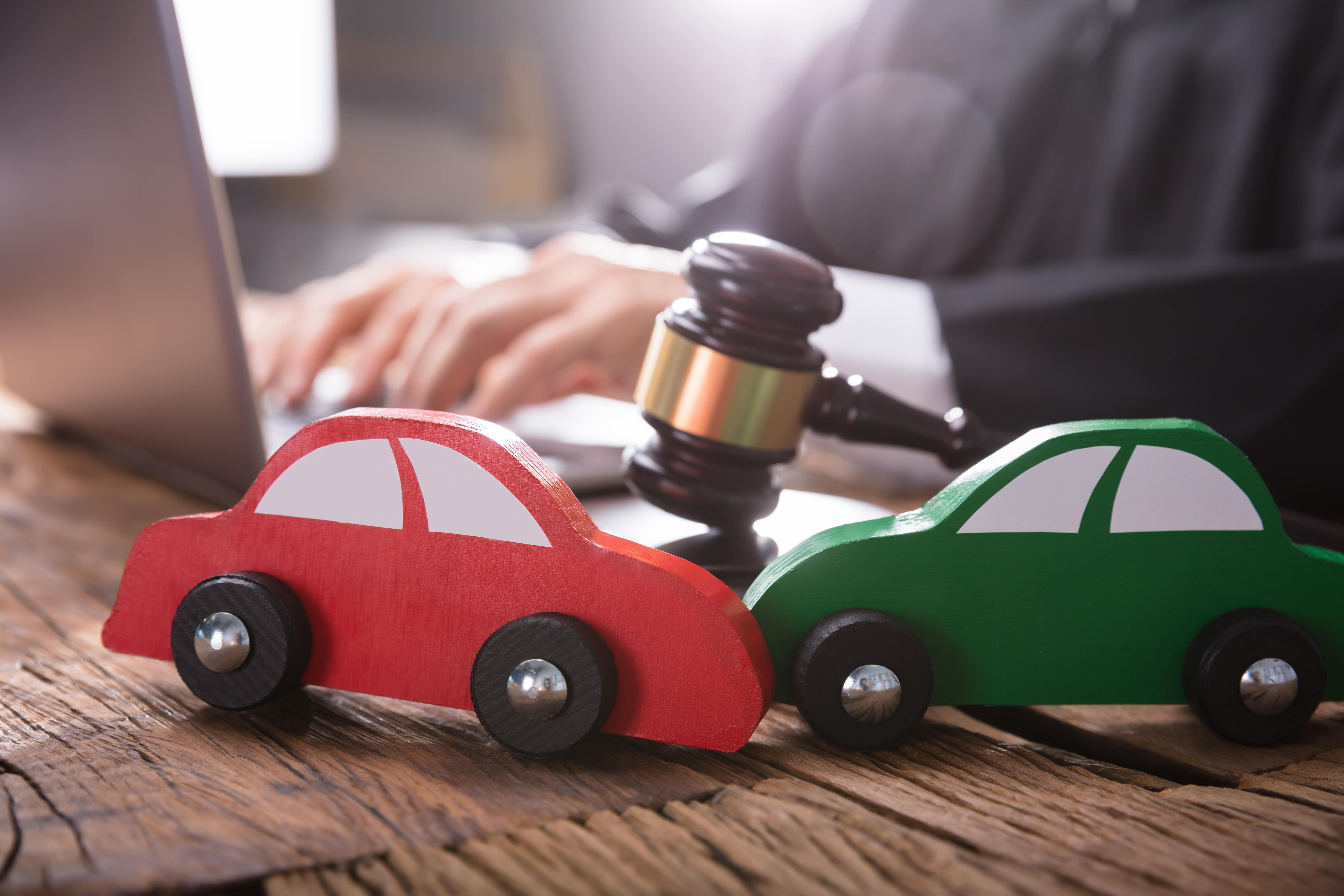 Two toy cars next to a gavel